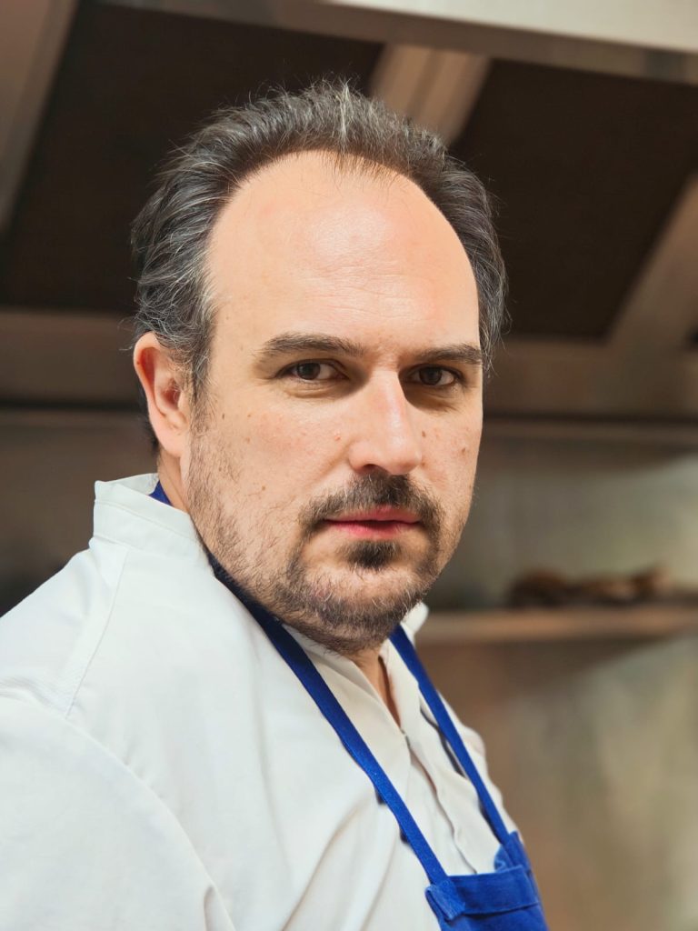 Chef Julien Lavandet professionnel souriant dans une cuisine professionnelle.