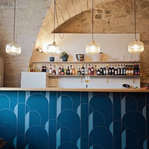 Un bar avec des bouteilles alignées et des lumières au-dessus.
