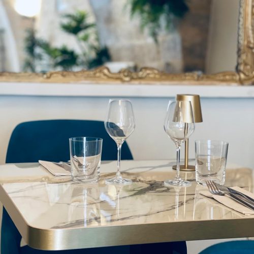 Une table avec des verres et une petite lampe dorée.
